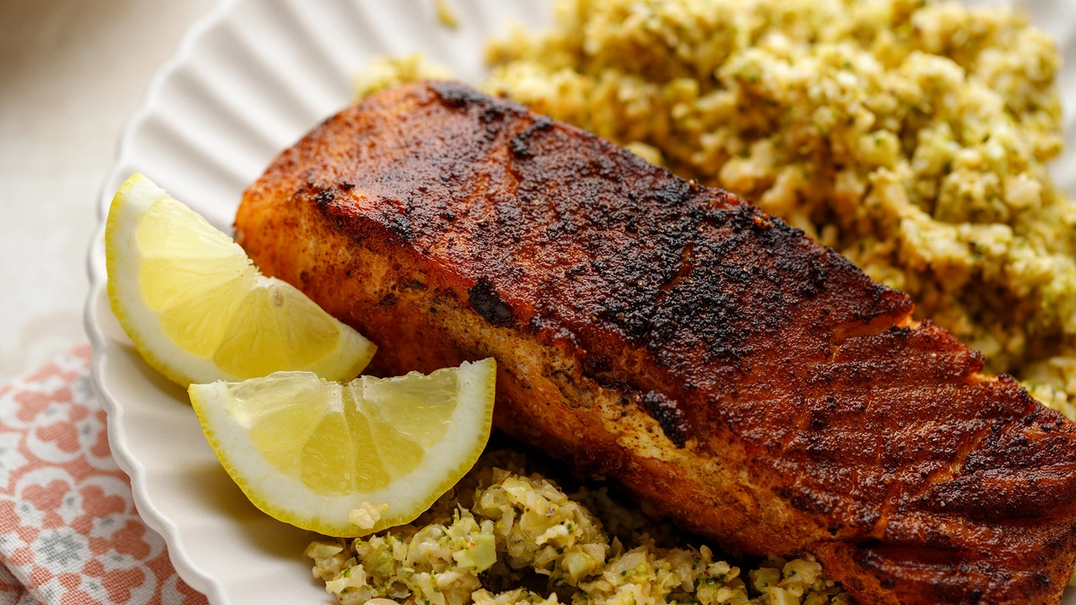 Blackened salmon with crispy skin, served alongside a warm slaw.